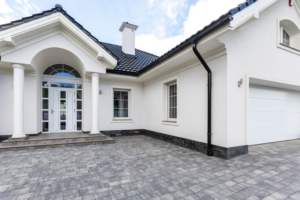 White house with a columned porch, glazed front door and white garage door