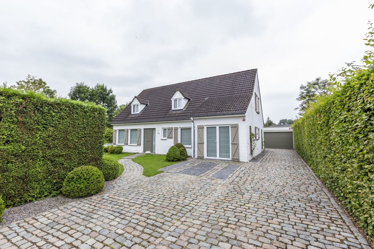 White dormer house with DAKO windows behind a hedged cobble drive