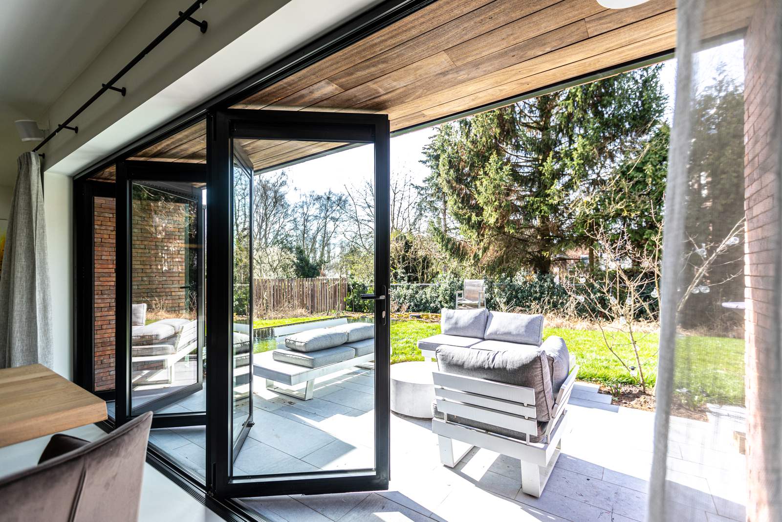 Black folding doors opened onto a garden terrace